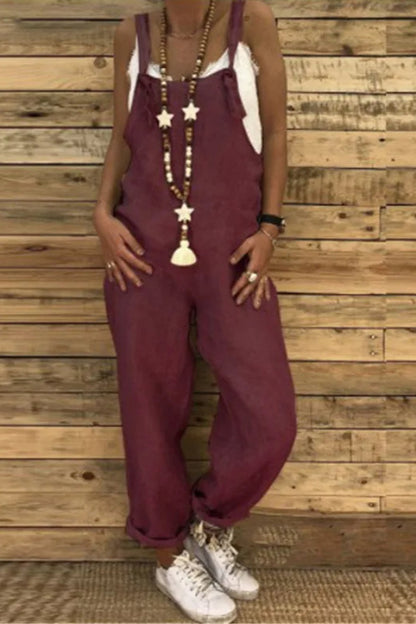 Person wearing maroon overalls with a wooden wall background