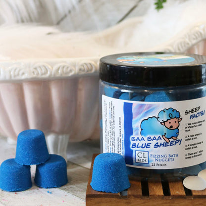 A container of gumdrop shaped blue sheep bath bombs with a tiny 3 bath bomb pyramid to its side