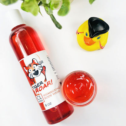 A transparent bottle and cup filled with our red orange tiger roar body wash against a white background