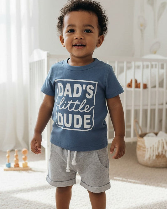 Calla Lily Cosmetics + CL kids blue graphic tee with "DAD'S little DUDE" text and grey shorts with drawstring. Cotton-polyester blend.