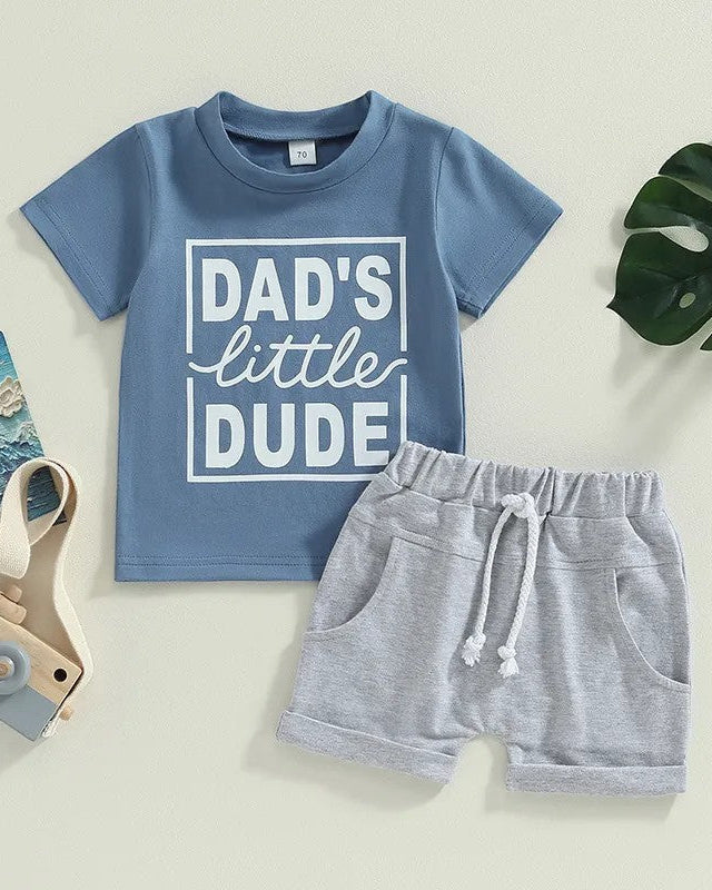 Blue shirt that says Dad's little dude with grey shorts