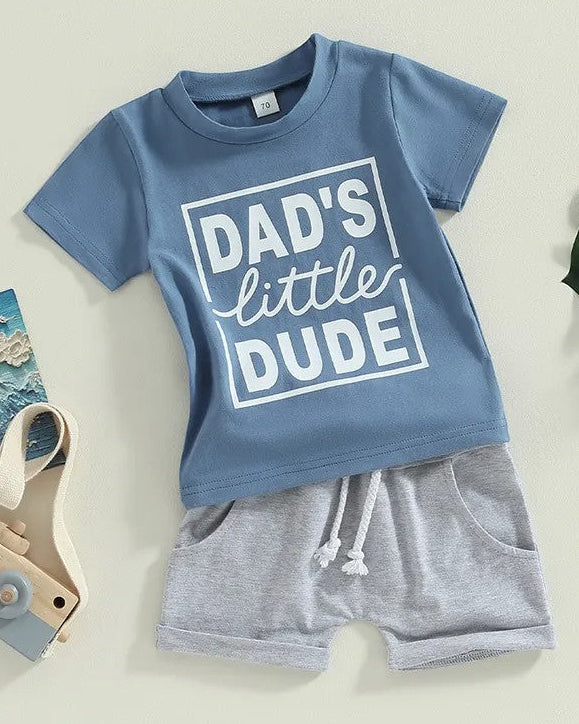 Blue shirt that says Dad's little dude with grey shorts