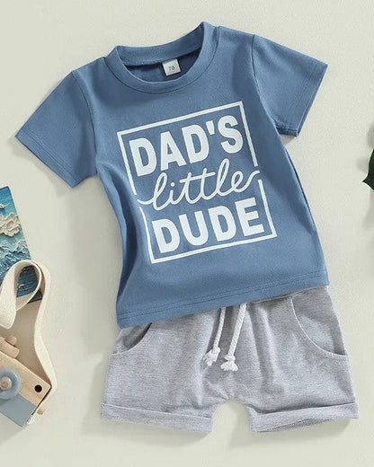 Blue shirt that says Dad's little dude with grey shorts