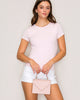A woman wearing a pink short sleeve crew neck tee and white shorts, holding a pink purse.