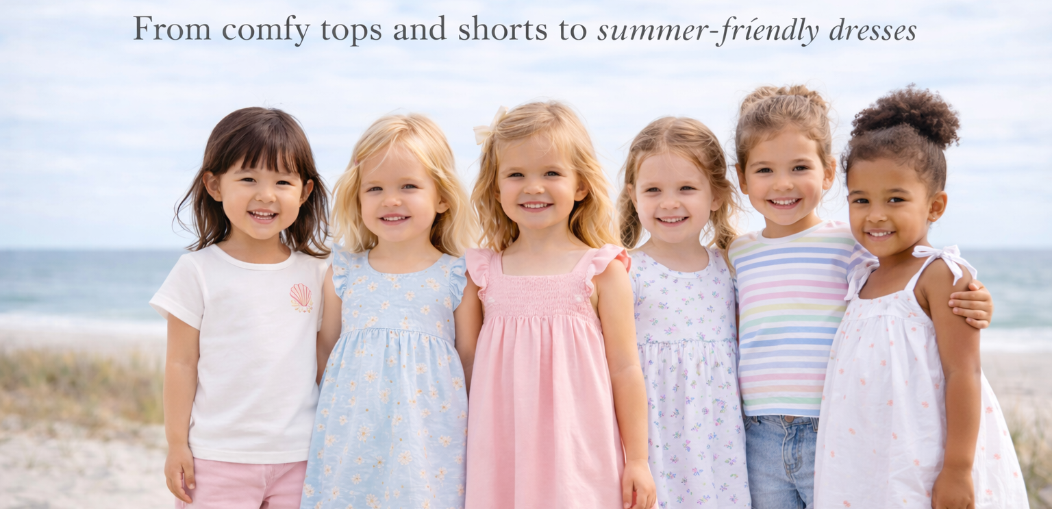 Group of six young girls wearing various toddler tops and dresses on a beach.