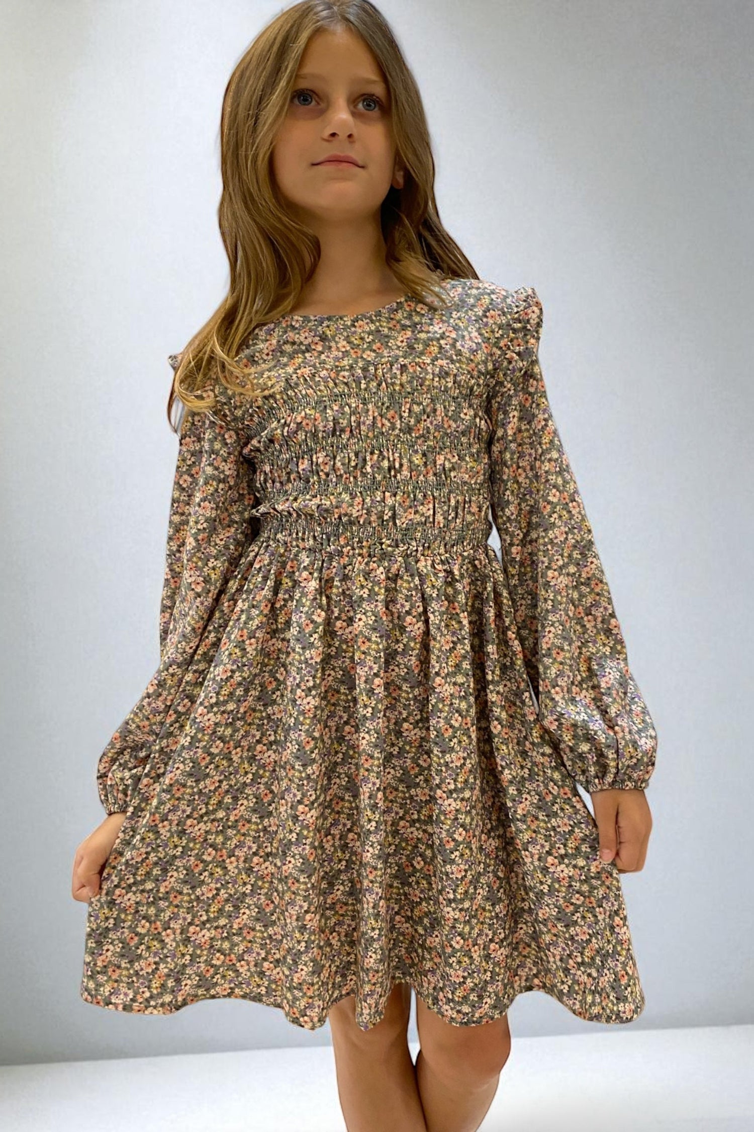 Young girl wearing a floral dress against a plain background