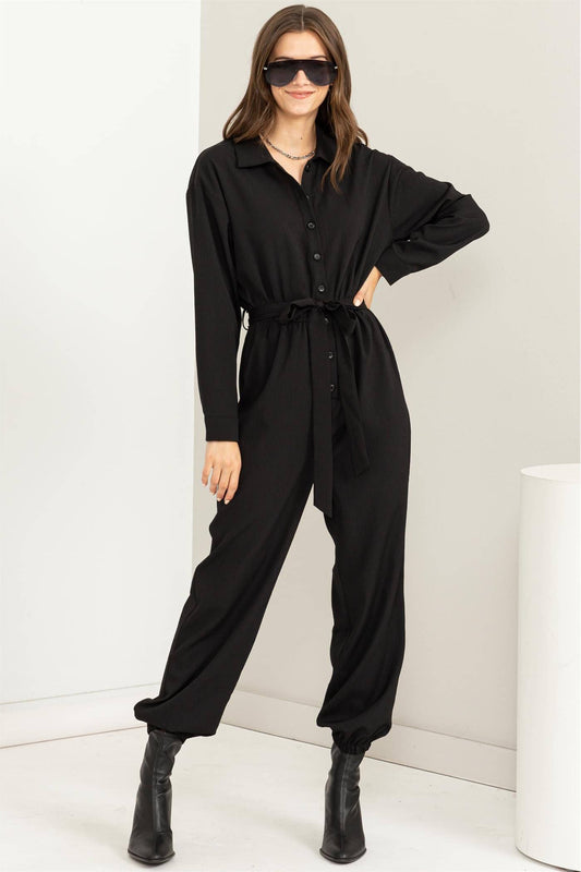 Woman wearing a black jumpsuit with a white background