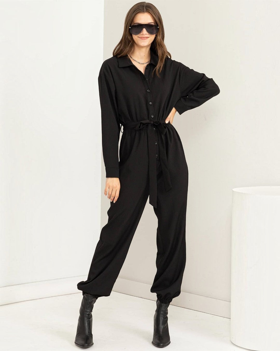 Woman wearing a black jumpsuit with a white background