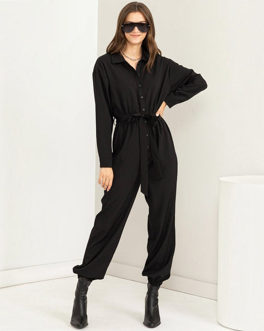 Woman wearing a black jumpsuit with a white background