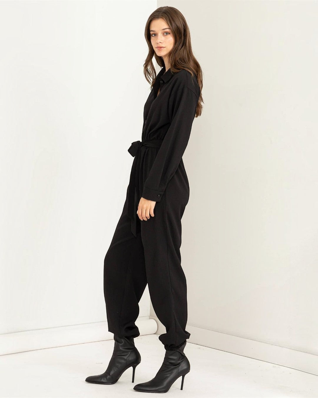 Woman wearing a black jumpsuit against a white background