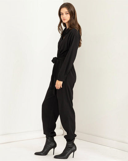 Woman wearing a black jumpsuit against a white background