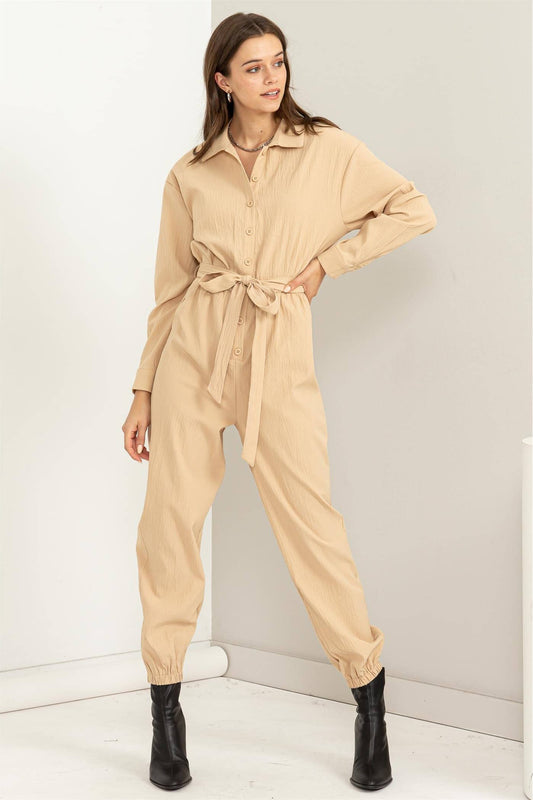 Woman wearing a beige jumpsuit against a white background