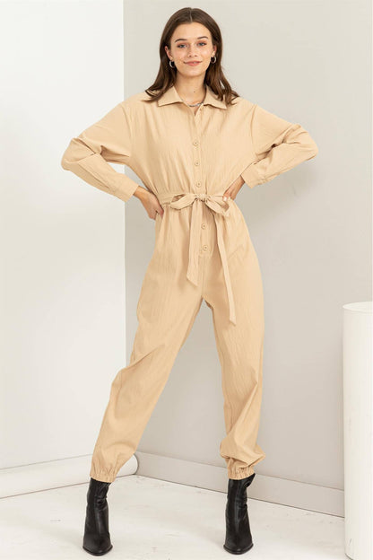 Woman wearing a beige jumpsuit against a white background