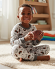 Child in pajamas holding a football in a room with a bookshelf and toys.
