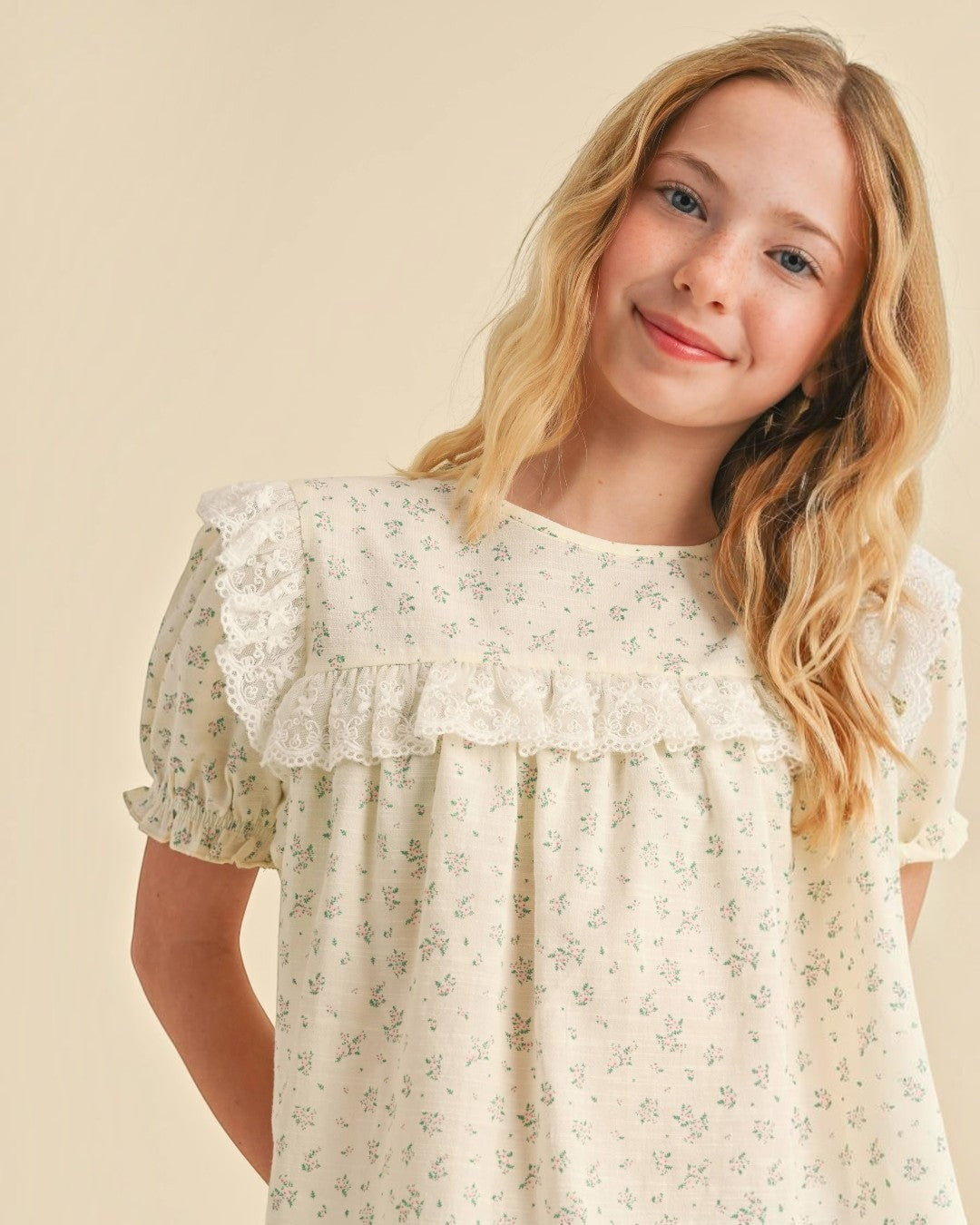 Young girl wearing a floral dress against a beige background