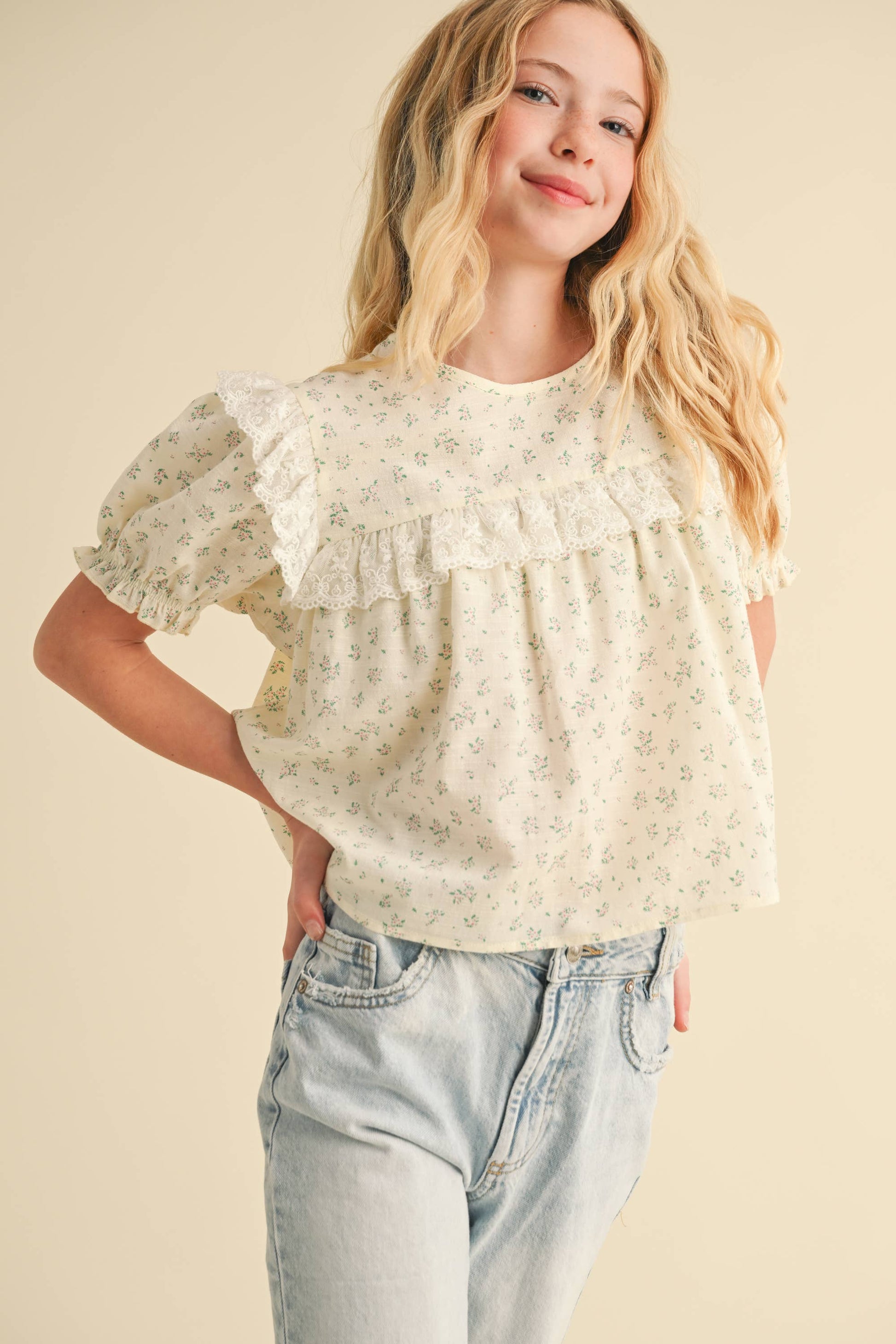 Woman wearing a floral blouse and jeans on a beige background