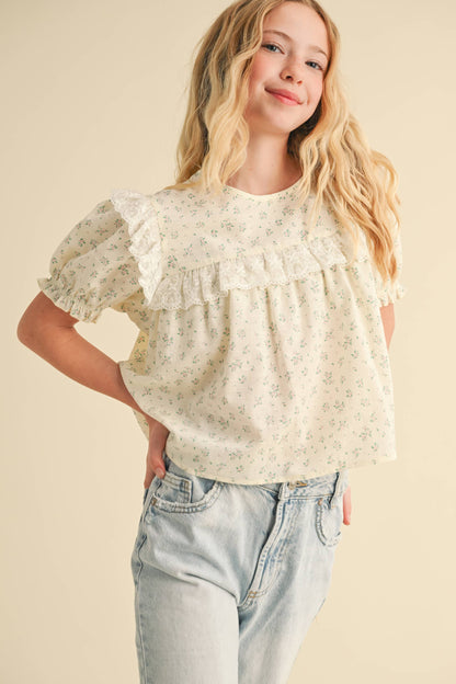 Woman wearing a floral blouse and jeans on a beige background