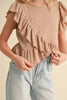 Person wearing a ruffled top and jeans on a beige background