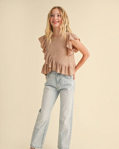 Young girl wearing a ruffled top and jeans on a beige background