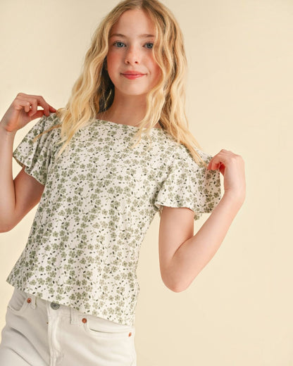 Young girl wearing a floral blouse against a beige background