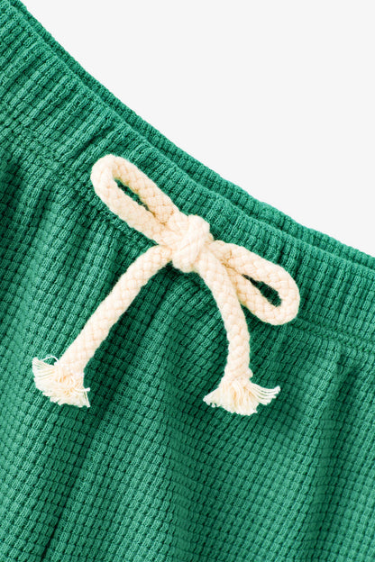 Green textured fabric with a white drawstring on a light gray background