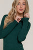 Woman wearing a green cable knit sweater against a plain background