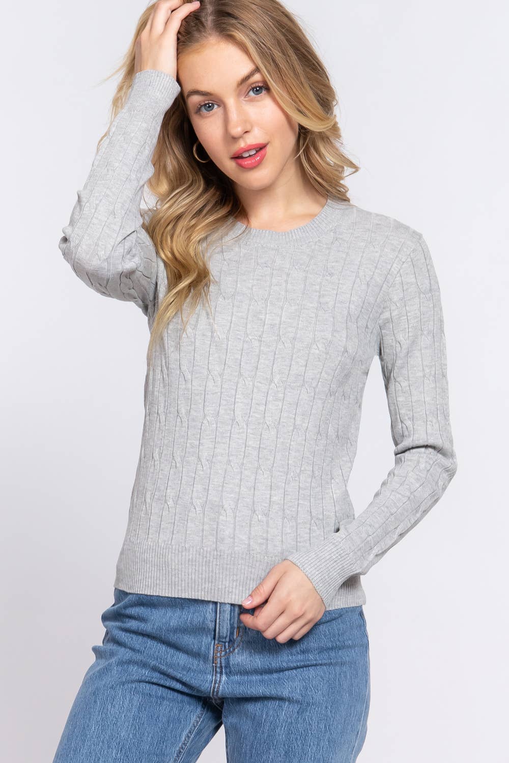 Woman wearing a gray sweater and blue jeans on a white background