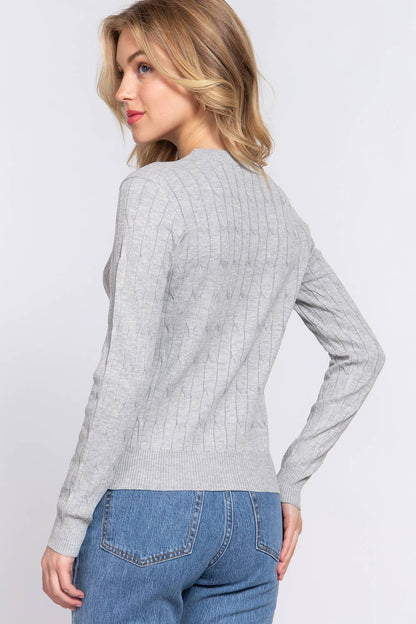 Woman wearing a gray sweater and blue jeans on a light gray background