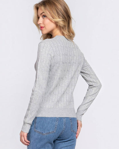 Woman wearing a gray sweater and blue jeans on a light gray background