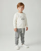 Children's outfit with cream sweatshirt and gray jogger pants on a white background