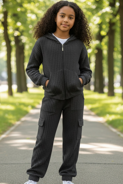 Child wearing a dark gray tracksuit standing on a path with trees in the background