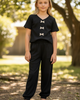 Young girl wearing a black outfit with bow details in a park setting