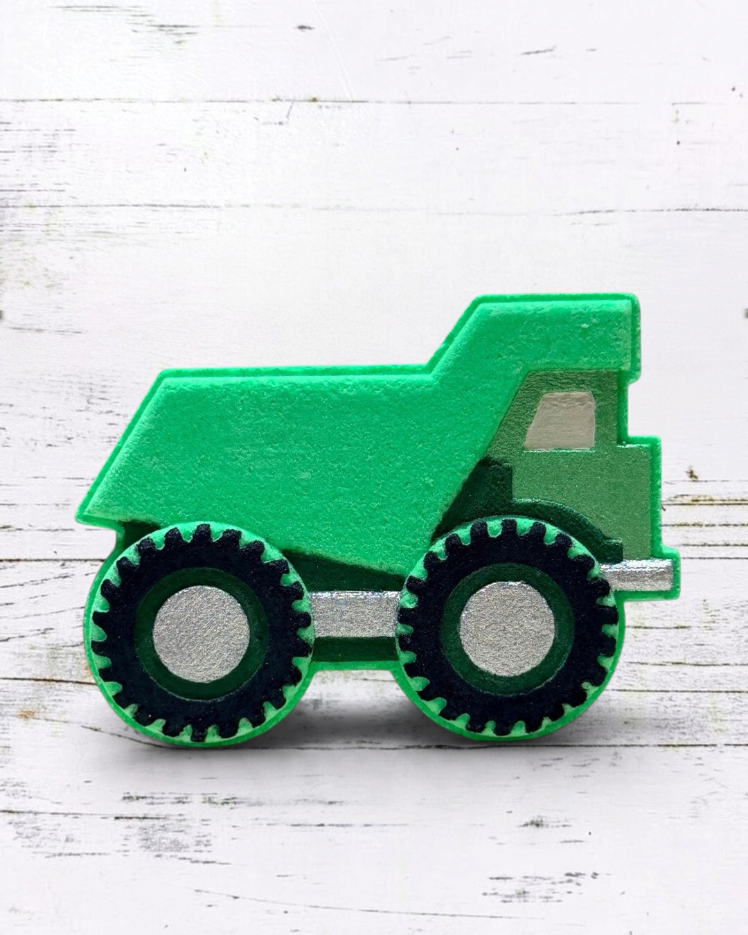 Calla Lily Cosmetics + CL kids green dump truck shaped bath bomb with black and silver details on a white wood surface