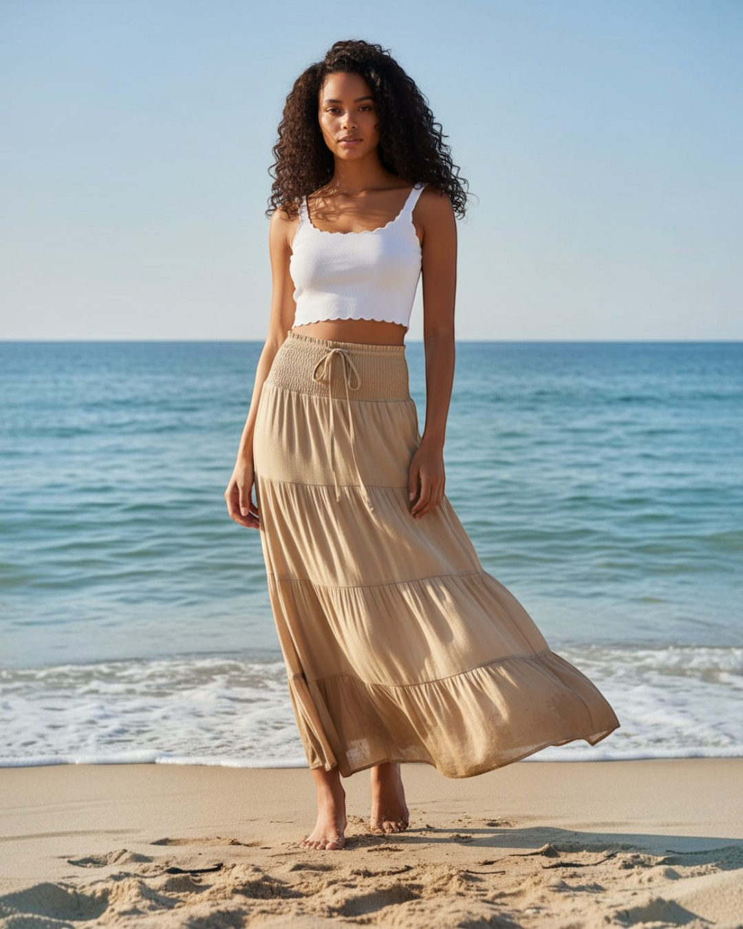 Calla Lily Cosmetics + CL kids ivory smocked tiered maxi skirt on a model standing on a sunny beach.