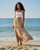 Calla Lily Cosmetics + CL kids ivory smocked tiered maxi skirt on a model standing on a sunny beach.