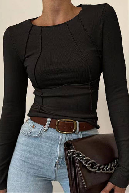 Person wearing a black long-sleeve top and light blue jeans, holding a brown handbag with a chain detail.