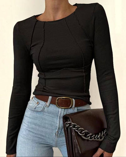 Person wearing a black long-sleeve top and light blue jeans, holding a brown handbag with a chain detail.