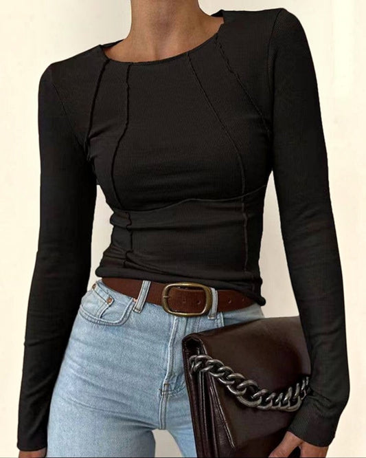 Person wearing a black long-sleeve top and light blue jeans, holding a brown handbag with a chain detail.