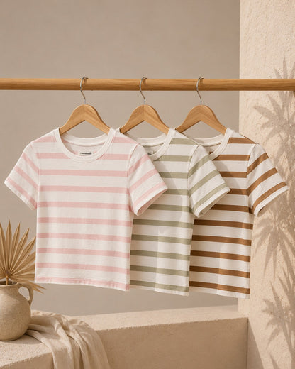 Three striped t-shirts hanging on a rack against a beige wall.