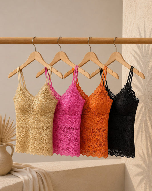 Five lace camisoles in gold, pink, orange, and black hanging on a rack against a neutral background.