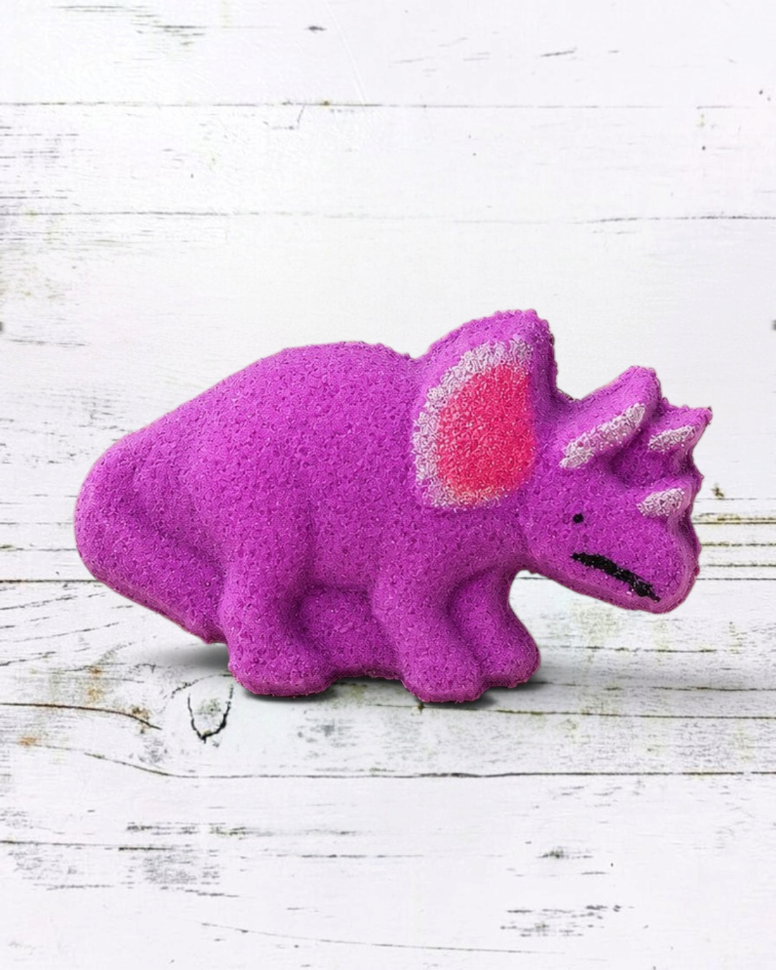 Calla Lily Cosmetics + CL kids purple triceratops dinosaur bath bomb with grape scent on a beige tray