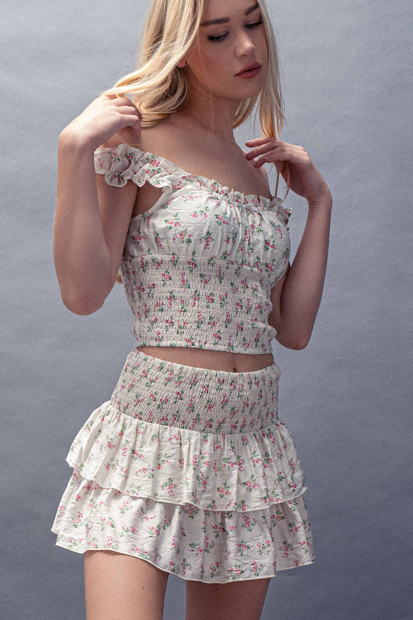 Woman wearing a floral two-piece outfit against a gray background