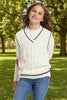 Young girl wearing a white sweater vest over a white shirt with blue trim on a white background