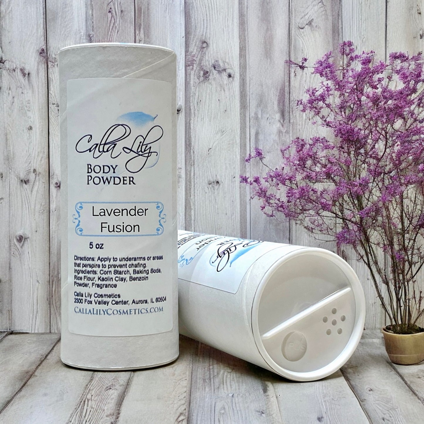 Body powder container labeled 'Lavender Fusion' by Calla Lily Cosmetics on a wooden surface with a wooden wall background.