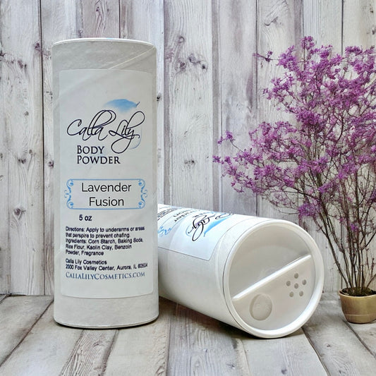 Body powder container labeled 'Lavender Fusion' by Calla Lily Cosmetics on a wooden surface with a wooden wall background.