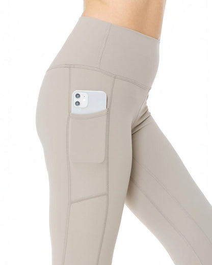 Beige leggings with a pocket holding a phone on a white background