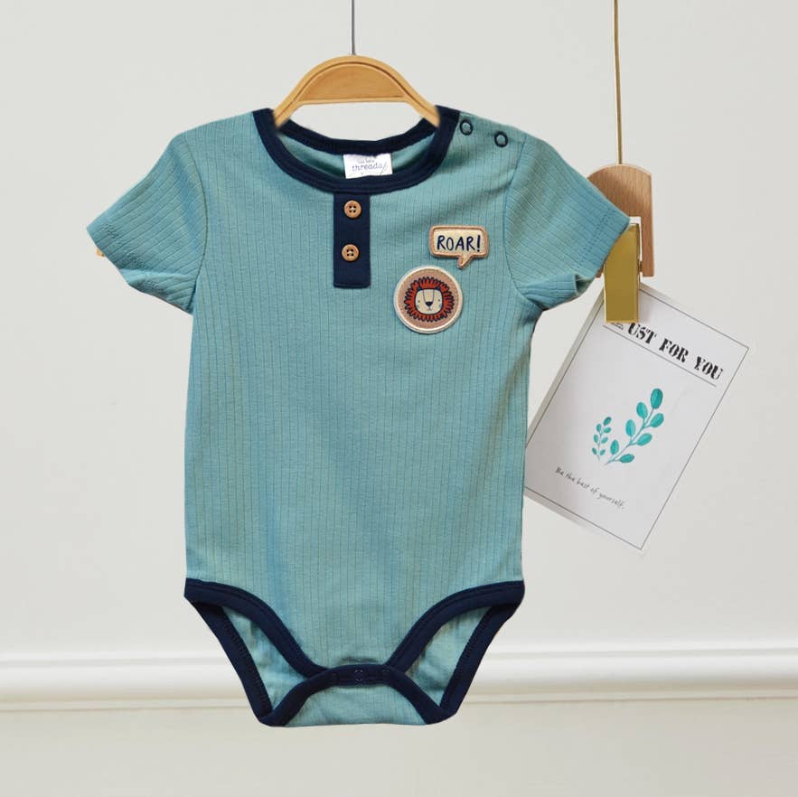 Blue baby onesie with lion design on a hanger against a white wall.