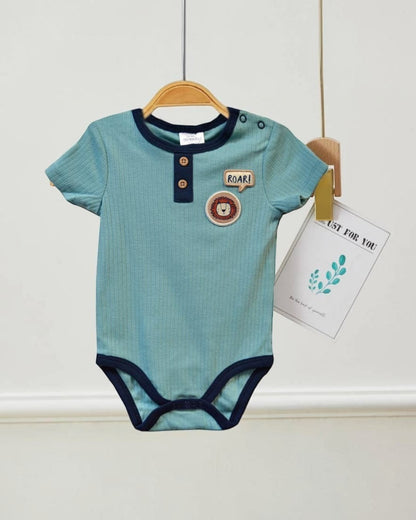 Blue baby onesie with lion design on a hanger against a white wall.