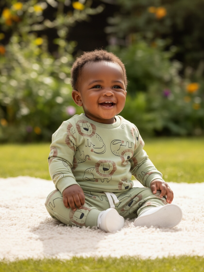 Baby sitting on a blanket outdoors with a garden background
