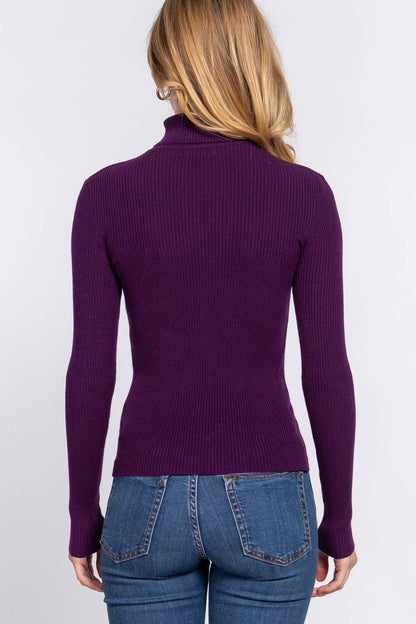 Person wearing a purple ribbed sweater and blue jeans on a white background
